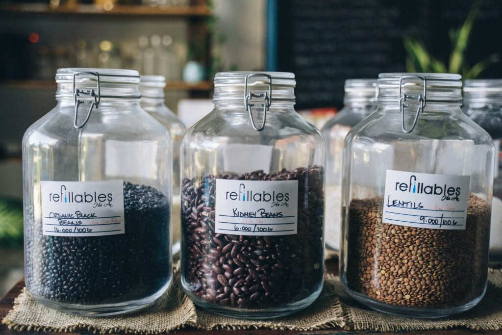 Three refillable glass jars with organic black beans, kidney beans, and lentils in a shop setting.