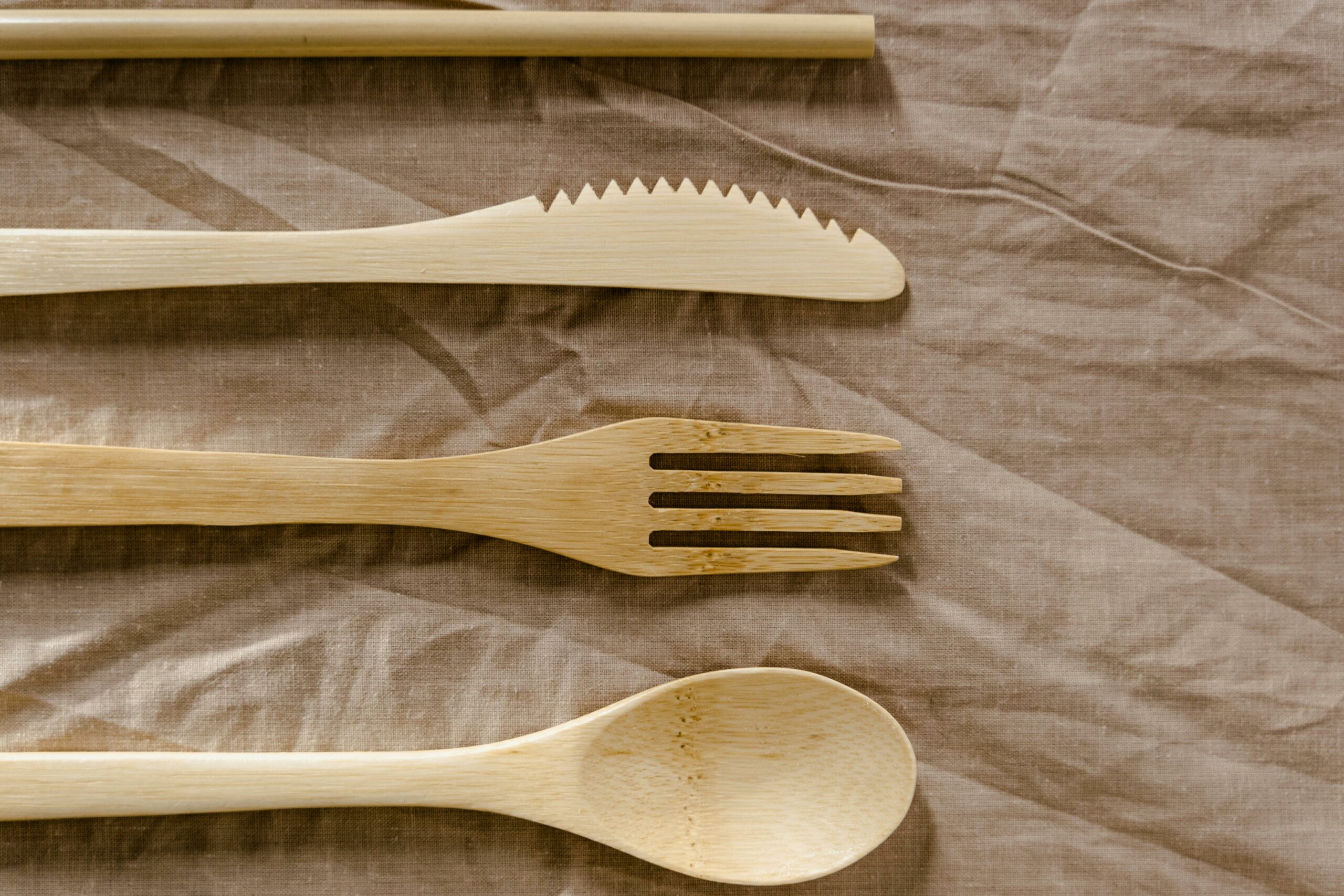 Top view of eco-friendly wooden utensils placed on textured textile, showcasing natural design.